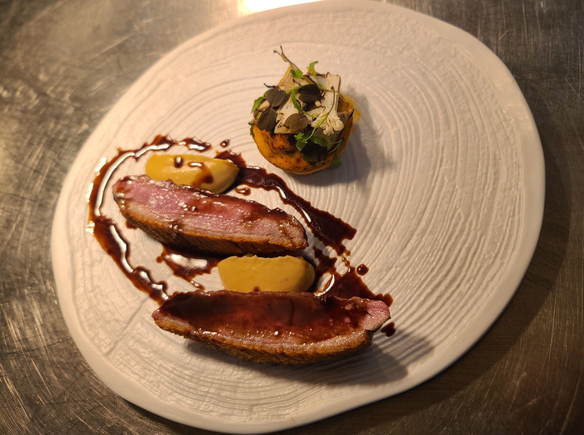 Sliced duck with garnish on a wide white plate