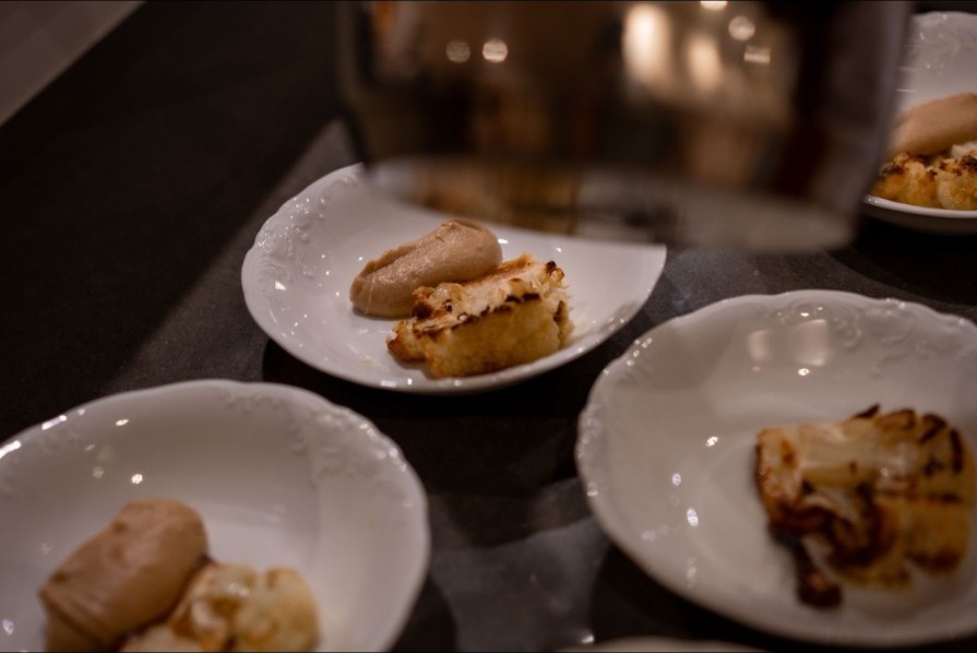 Plates of fish and cauliflower at a dim table